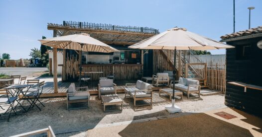 Fauteuils de jardin et tables basses sous des parasols devant le comptoir de restauration.