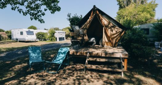 Tente bivouac sur une plateforme en bois avec deux chiliennes turquoise devant la terrasse.