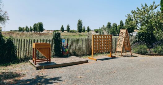 Jeux en bois de grand format installés en extérieur, le long d’une clôture et de la végétation.